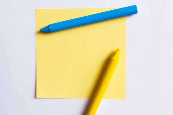 Top view of blue and yellow crayons near paper note isolated on white — Stock Photo