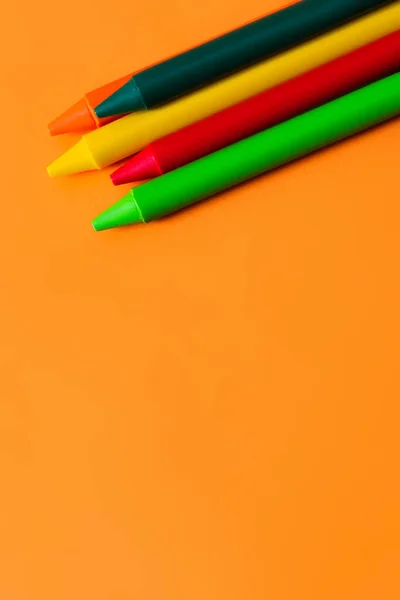 Vue de dessus de l'ensemble avec des crayons de cire colorés sur fond orange — Photo de stock
