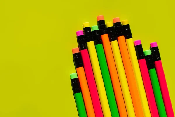 Ansicht von Buntstiften mit Radiergummis auf grünem Hintergrund — Stockfoto