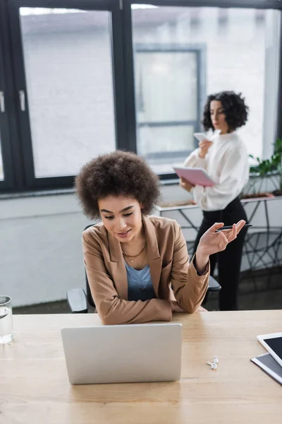 Afroamericana empresaria teniendo videollamada en laptop en oficina - foto de stock