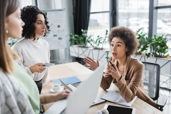 African american businesswoman talking to multiethnic colleagues with gadgets in office — Stock Photo