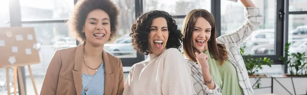 Mulheres de negócios multiculturais alegres em pé no escritório, banner — Fotografia de Stock