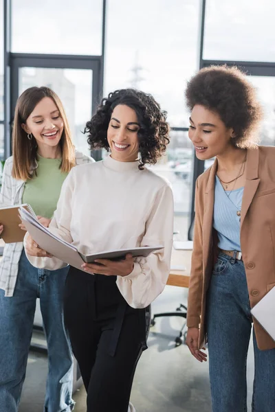 Positive multiethnic businesswomen looking at papers in office — Stock Photo