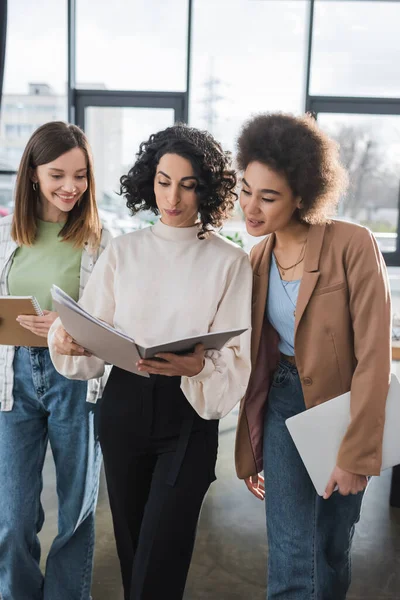 Mujeres de negocios interraciales mirando la carpeta de papel en la oficina - foto de stock