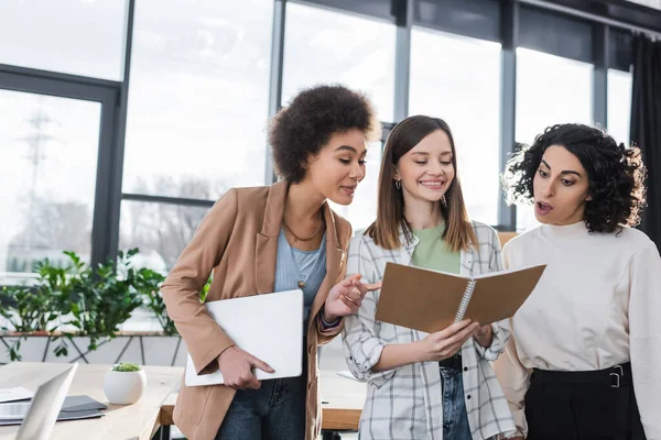 Multicultural businesswomen looking at notebook in office — Stock Photo