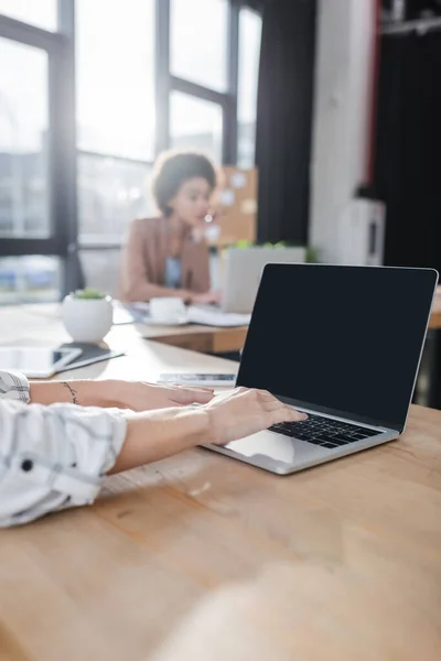 Businesswoman using laptop with blank screen in office — Photo de stock