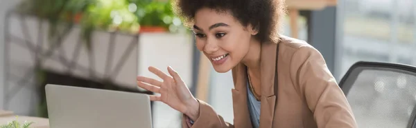 Alegre mujer de negocios afroamericana tener chat de vídeo en el ordenador portátil en la oficina, bandera - foto de stock