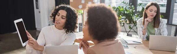 Arabian businesswoman holding digital tablet near multicultural colleagues in office, banner — Foto stock