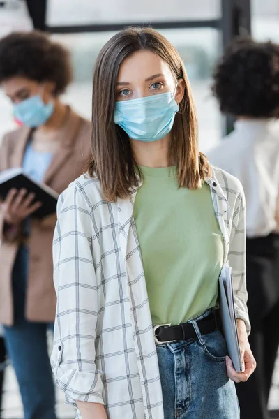 Giovane donna d'affari in maschera medica in possesso di cartella di carta in ufficio — Foto stock