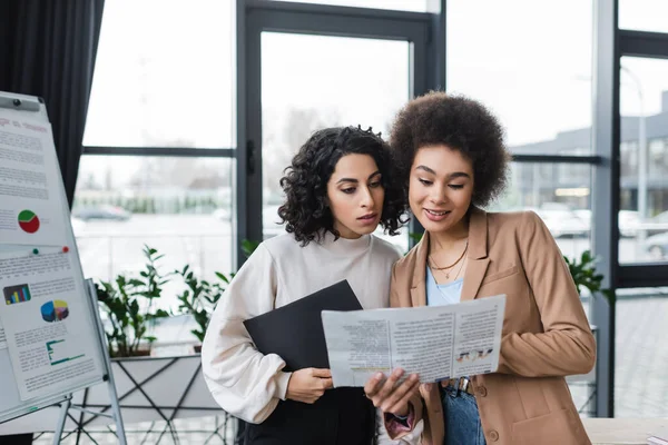 Multiethnic businesswomen reading newspaper in office — Photo de stock