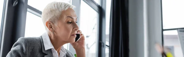 Banquier senior avec cheveux gris court parlant sur smartphone au bureau, bannière — Photo de stock
