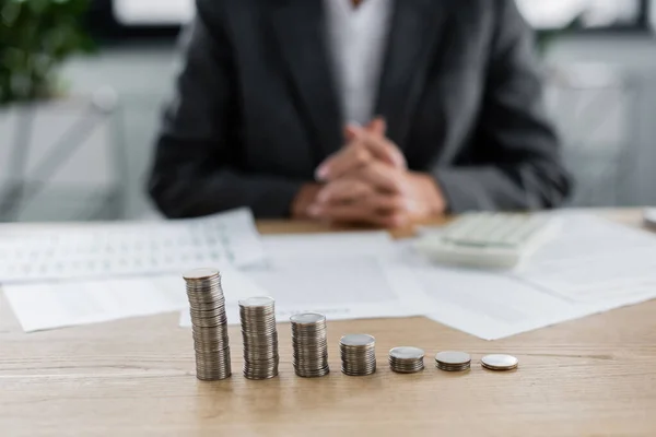 Piles de pièces d'argent près banquier recadré assis sur fond flou — Photo de stock