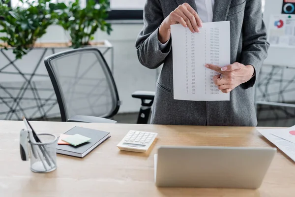 Cropped view of economist pointing at document during online conference on blurred flip chart — Stock Photo