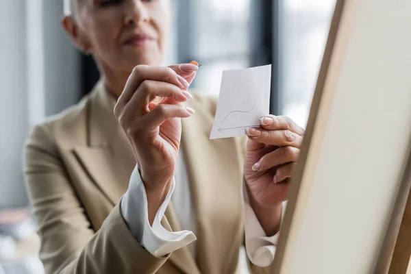 Selective focus of paper note and pushpin in hands of cropped banker on blurred background — Fotografia de Stock