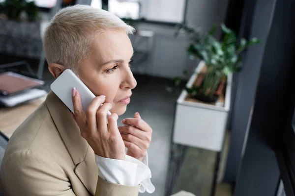 Premurosa donna d'affari che chiama sul cellulare in ufficio sfocato — Foto stock