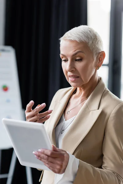 Entmutigte Geschäftsfrau gestikuliert nahe digitalem Tablet im Büro — Stockfoto