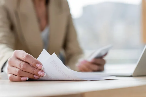 Vista ritagliata del banchiere che lavora con documenti e gadget sfocati in ufficio — Foto stock