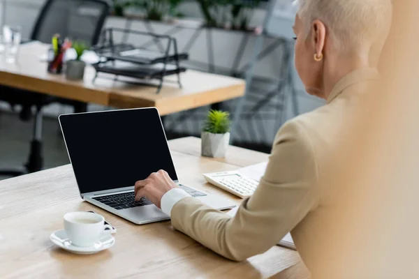 Старший бухгалтер використовує ноутбук з порожнім екраном біля чашки кави — стокове фото