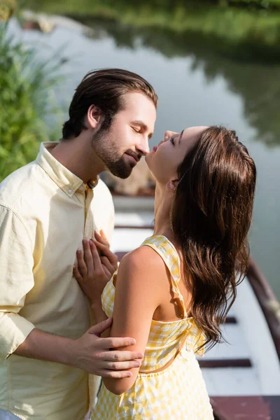 Mujer alegre con los ojos cerrados abrazando con novio - foto de stock