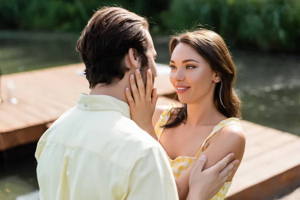 Mujer alegre y sensual tocando la cara del novio - foto de stock