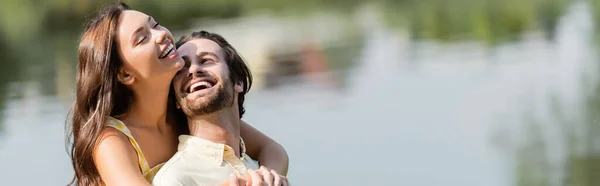 Jeune femme étreignant heureux copain barbu près du lac, bannière — Photo de stock