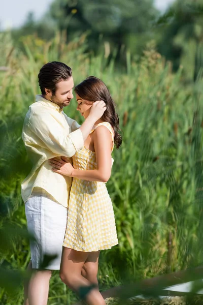 Homme barbu regardant jeune copine en robe près du lac — Photo de stock