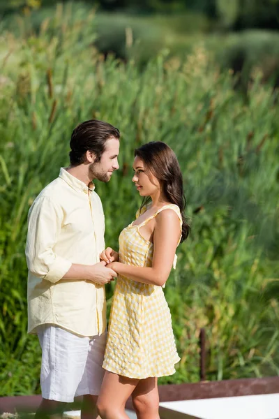 Jeune couple se tenant la main et se regardant dans le parc — Photo de stock