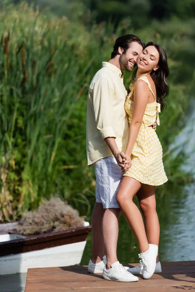 Cheerful couple hugging and holding hands outside — Stock Photo