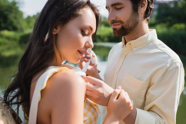 Bearded man tying ribbon on dress of happy woman — Stock Photo