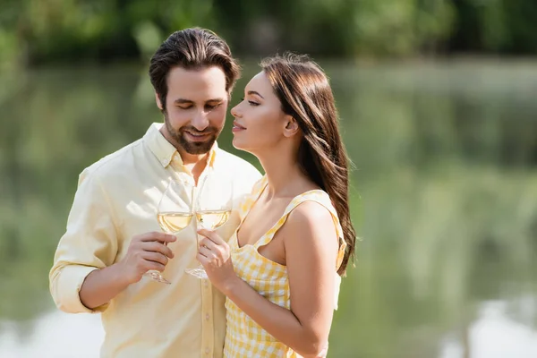 Jeune couple en vêtements d'été cliquetis verres avec du vin — Photo de stock