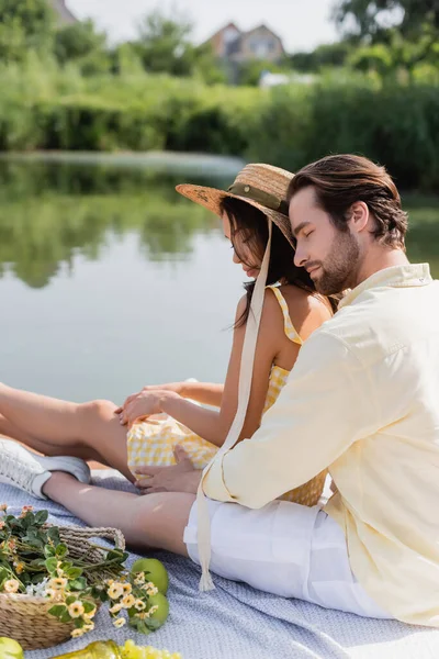 Romantic couple sitting on pier near lake during picnic — Stock Photo