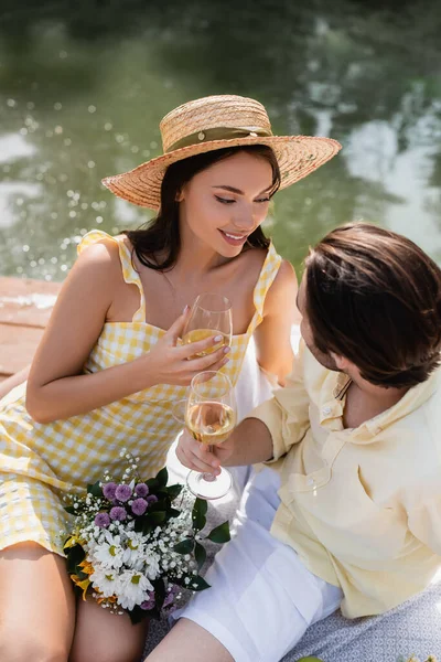 Vue grand angle du couple romantique tenant des verres de vin près du bouquet de fleurs — Photo de stock