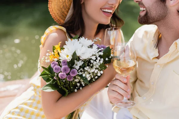 Vista cortada de mulher segurando buquê de flores e óculos de clinking com namorado — Fotografia de Stock