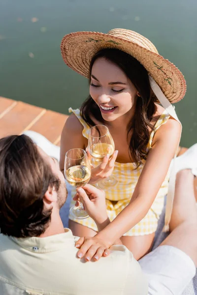 Vue grand angle du couple romantique souriant et tenant des verres de vin près du lac — Photo de stock