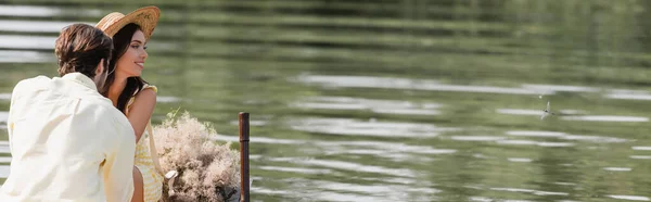 Lächelnde Frau mit Strohhut, die während einer Bootsfahrt in der Nähe ihres romantischen Freundes wegschaut, Banner — Stockfoto