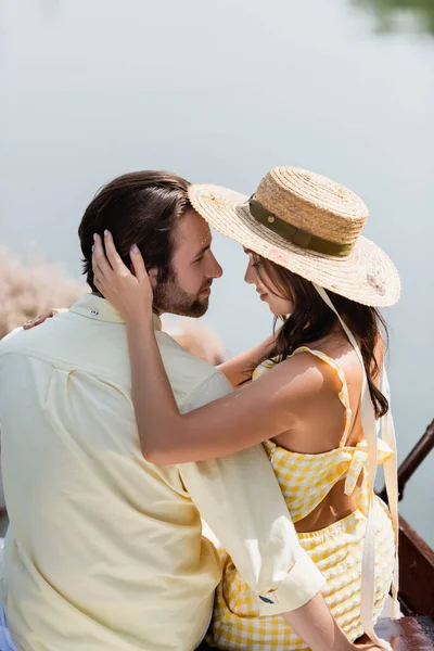 Усміхнена молода жінка в сонячному капелюсі обіймає чоловіка — стокове фото