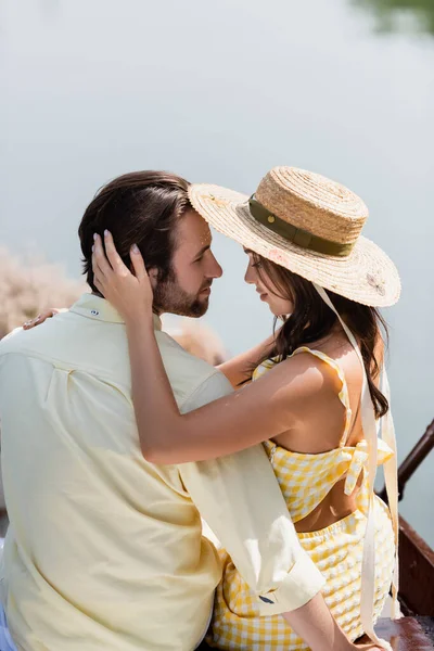 Sourire jeune femme dans chapeau de soleil étreignant l'homme — Photo de stock