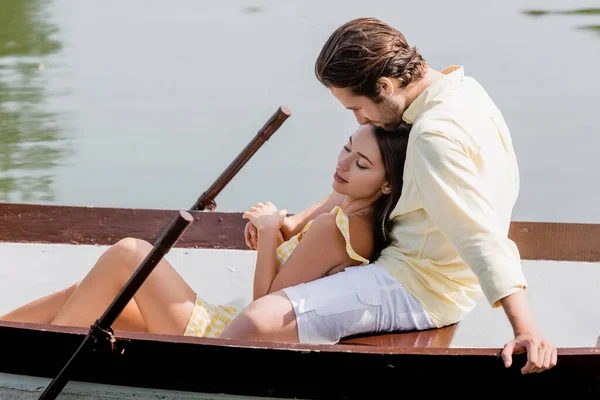 Young woman with closed eyes lying in boat with boyfriend — Stock Photo