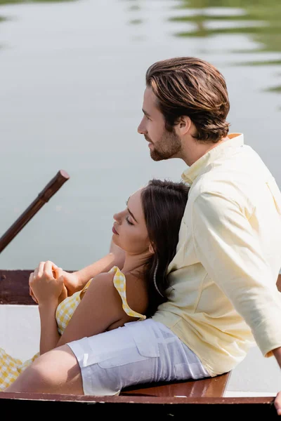 Vista lateral de la joven mujer acostada en barco con su novio - foto de stock