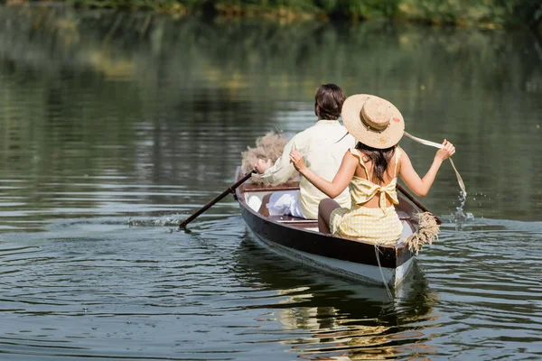 Vue arrière de la femme en chapeau de paille ayant promenade en bateau avec petit ami — Photo de stock