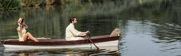 Vista lateral de la pareja que tiene paseo romántico en barco en el lago, bandera - foto de stock