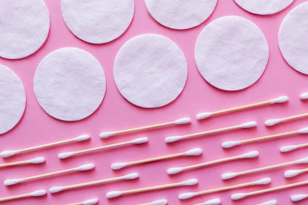 Rows of white cotton pads and ear sticks on pink background, top view - foto de stock