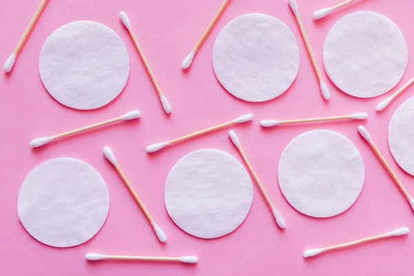 Top view of plenty of ear sticks and cotton pads on pink background - foto de stock