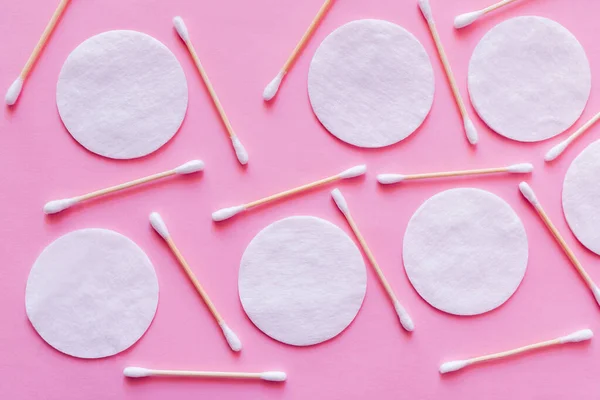 Vue de dessus de beaucoup de bâtons d'oreille et de coussinets de coton sur fond rose — Photo de stock