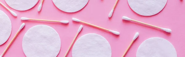 Top view of cosmetic cotton pads and hygienic ear sticks on pink background, banner - foto de stock
