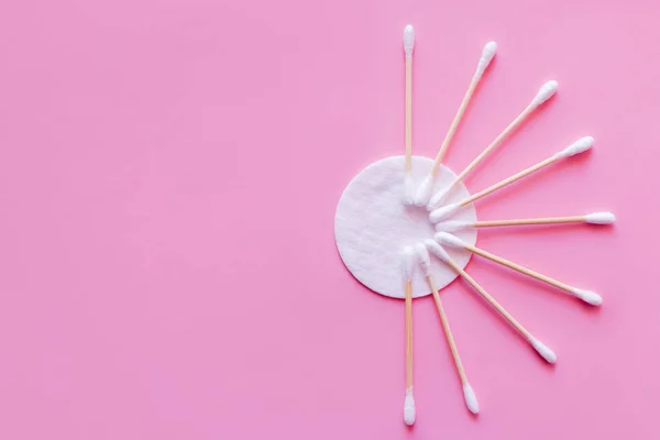 Top view of hygienic ear sticks near white cotton pad on pink background - foto de stock