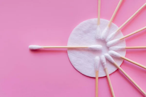 Top view of cosmetic cotton pad and ear sticks on pink background — Stock Photo