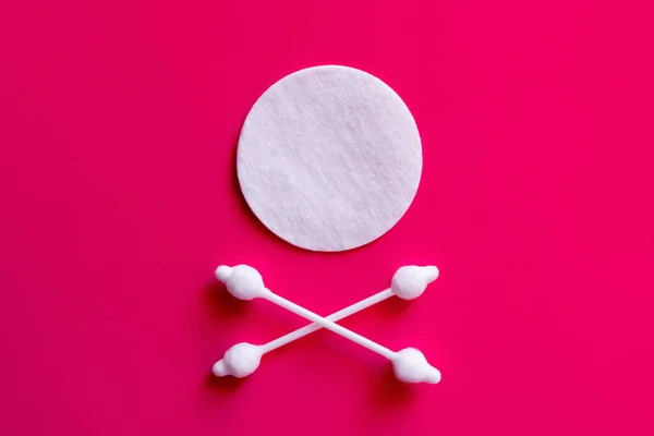 Bastoni auricolari incrociati sotto tampone di cotone bianco su sfondo rosa, vista dall'alto — Foto stock