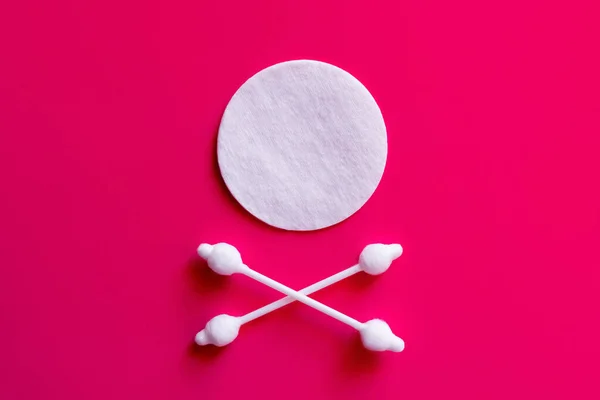 Crossed ear sticks under white cotton pad on pink background, top view — Foto stock