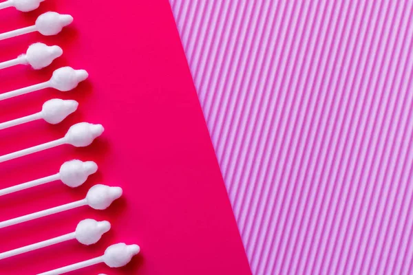 Vue du dessus des coton-tiges cosmétiques sur fond rose vif et violet — Photo de stock